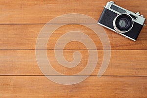 Office desk wooden table with old camera. Top view with copy space. Top view of old camera over wooden table. Retro vintage filter