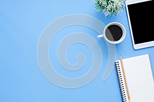 Office desk working space - Flat lay top view mockup photo of working space with tablet, coffee cup and notebook on blue pastel