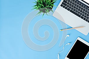 Flat lay top view mockup photo of working space with laptop, tablet and notebook placing on blue pastel background.