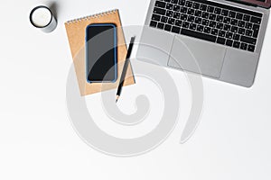 Office desk. Workplace with a modern laptop, candle, paper cup of coffee, notebook, pencil, smartphone