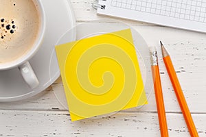 Office desk with yellow sticker, coffee and notepad
