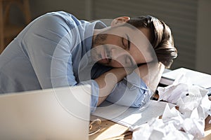 Office employee sleeping sit at desk put head on arms