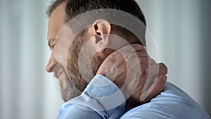 Office employee suffering from neck pain, working in front of computer, spasm