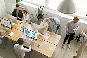 Office employees working together sharing desk using computers i