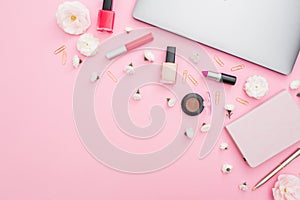 Office feminine desk with laptop, notebook, cosmetics and flowers on pink background. Top view. Flat lay concept.