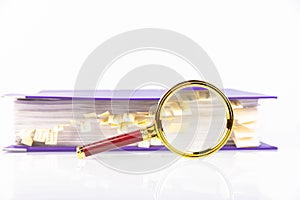 Office folder with documents with yellow bookmarks and a magnifying glass on a white table. White background