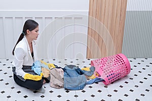 Office girl puts clothes in the basket to wash and clean.