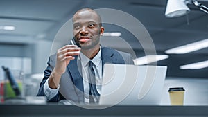 Office: Happy Successful Black Businessman Sitting at Desk Using Laptop Computer. African American