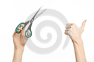Office and home topic: human hand holding a black scissors with blue accents on a white isolated background in studio