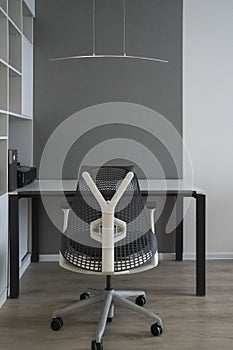 Office interior with modern comfortable workspace - computer desk, orthopaedic chair and natural daylight.