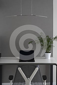 Office interior with modern comfortable workspace - computer desk, orthopaedic chair and natural daylight.