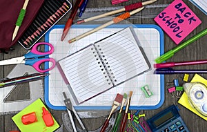 Office items with a white board on a wooden background.