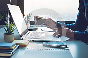 Office life concepts with person drinking coffee and using computer laptop on window