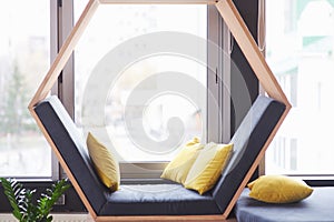 Office lounge interior office building or cafe, sofa chair in the form of a hexagon with pillows near the window