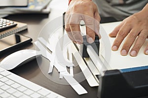 Office man using manual paper cutter or paper trimmer tool cutting white paper on black table