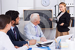 Office manager female is reading financial report to colleagues on meeting