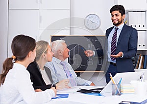 Office manager male is reading financial report to colleagues on meeting