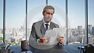 Office manager reading documents at panoramic window. Calm man drinking coffee