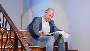 Office manager reading raport sitting on stairs