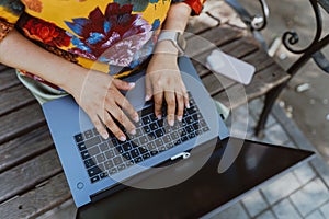 Office outdoors, close-up of female hands typing on a keyboard with a laptop in nature