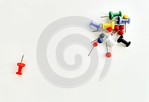 Office push pins on workplace. Top view isolated on white background. Concept: difference, isolation, individuality