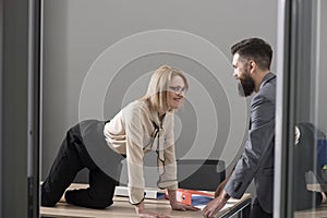 Office romance concept. secretary seduce boss in office. Businesswoman on desktop look at bearded businessman. Man