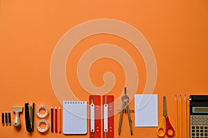 Office or school supplies on orange paperboard