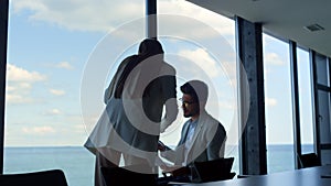 Office secretary showing businessman financial documents at panorama window.