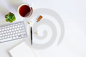 Office space with computer, coffee, mobile phone, pen and cactus over the white wooden table.