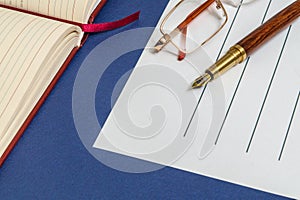 Office still life blue table with notebook and gilded pen on which a glasses is preparing for the notes