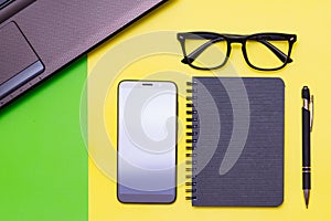 Office stuff with pen, paper notebook,smartphone,laptop eyeglasses.Top view.Working colorful desk table