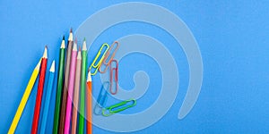 Office supplies concepts, Colored crayon pencils and clips on blue background