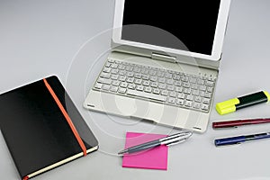 Office supplies consisting of tablet with keyboard, fluorescent marker, red and blue markers, modern pen, sticky notepad and note photo