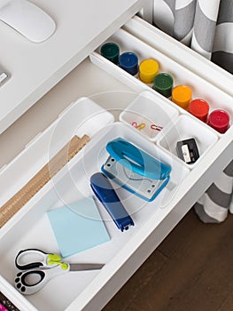 Office supplies are laid out in a white plastic container in the shelf of the desk. Back to school.