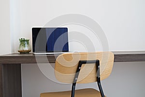 Office table with blank screen laptop, modern chair and garden p