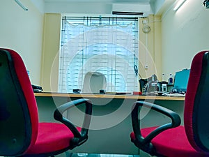 An office table and chairs with a big window behind the boss's chair