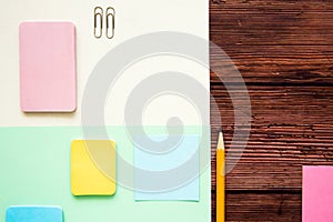 Office table with colored paper, pencil and writing materials. Top view with copy space.