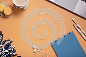 Office table desk with blank blue paper note pad, plaid, cup, pen, pc on colored background. Top view and copy space for text