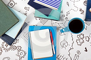 Office table desk with blue supplies, white blank note pad, cup, pen, pc, crumpled paper, flower on wooden background