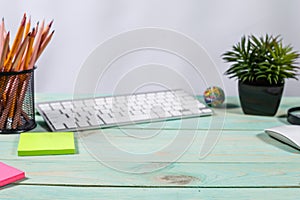 Office table desk with set of colorful supplies, flower on blue