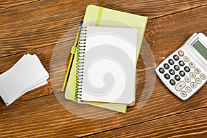 Office table desk with set of colorful supplies, white blank note pad, cup, pen, pc, crumpled paper, flower on wooden