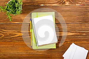 Office table desk with set of colorful supplies, white blank note pad, cup, pen, pc, crumpled paper, flower on wooden