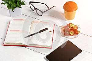 Office table desk with set of supplies, white blank notepad, cup, pen, tablet, glasses, flower on white background. Top