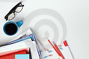 Office table desk with supplies, blank note pad, cup, pen, pc, crumpled paper, flower on white background. Top view