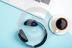 Office table desk. Workspace with laptop,office supplies, headphones and coffee cup on blue background. Top view, flat