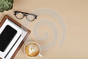 Office table desk, workspace with mobile phone, notebook, pencil, green plant, coffee and eyeglass