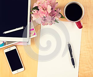 Office table with digital tablet, smartphone empty sheet of paper and cup of coffee. View from above