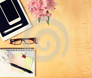 Office table with digital tablet, smartphone, reading glasses and notepad. View from above