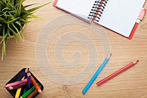 Office table with flower, blank notepad and colorful pencils