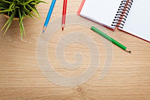 Office table with flower, blank notepad and colorful pencils